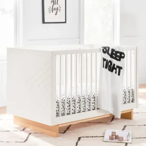 White BabyBliss Convertible Crib shown in a cozy nursery setting with soft pastel tones. The crib features a timeless design with slatted sides and a sturdy construction, offering versatility with its ability to convert from a crib to a toddler bed. Ideal for growing children, this crib blends classic style with modern functionality, creating a serene and safe sleep environment.