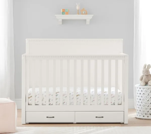 PureComfort 4-in-1 Convertible Storage Crib in a neutral wood finish, featuring built-in storage drawers and a sleek, modern design. The crib is staged in a cozy nursery setting with soft bedding and plush toys, showcasing its versatility and space-saving functionality.